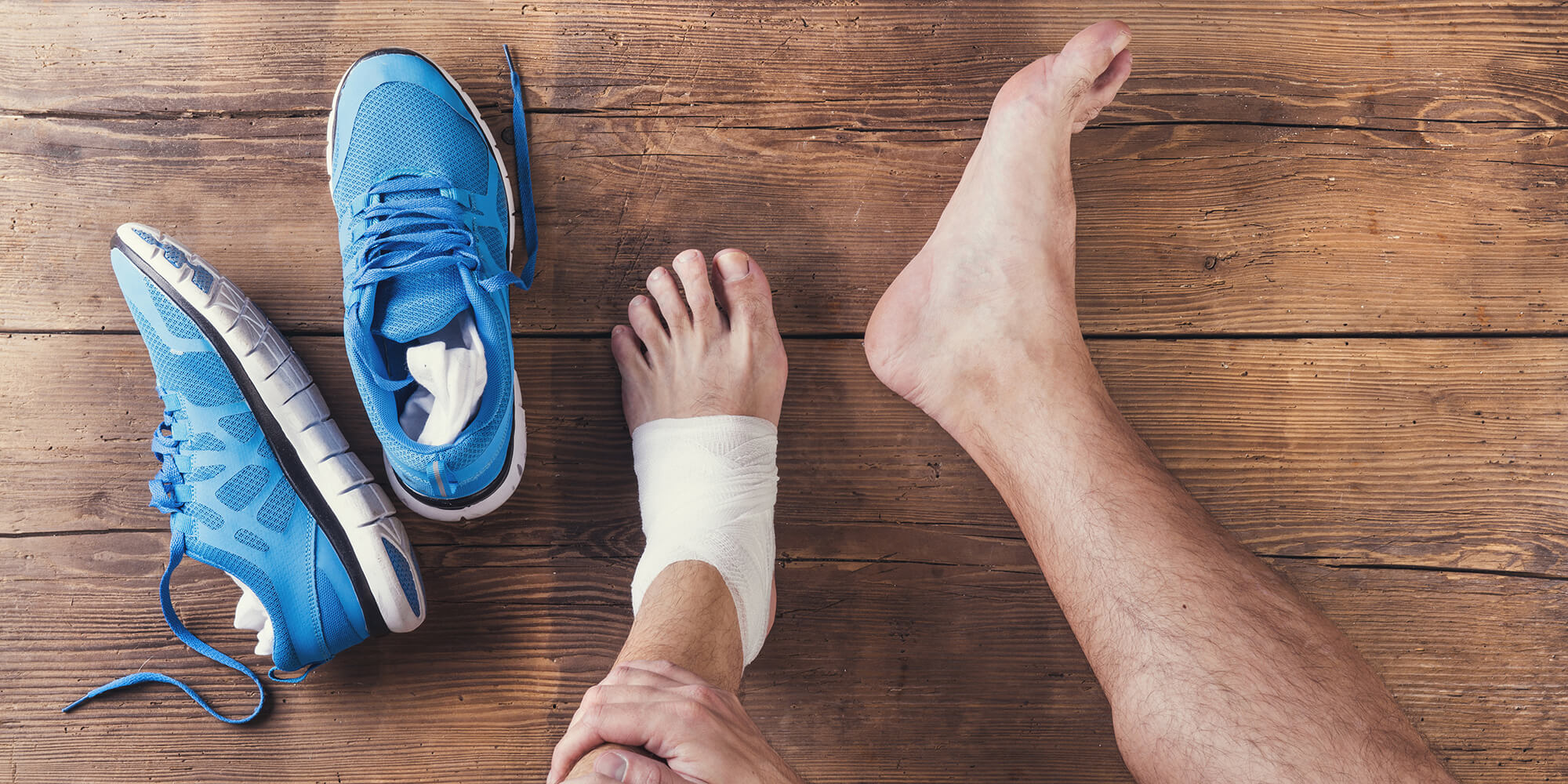 Clinique podiatrique Stéphanie Brodeur | Gros plan sur les pieds nus d'un homme blessé et chaussures de sport bleues