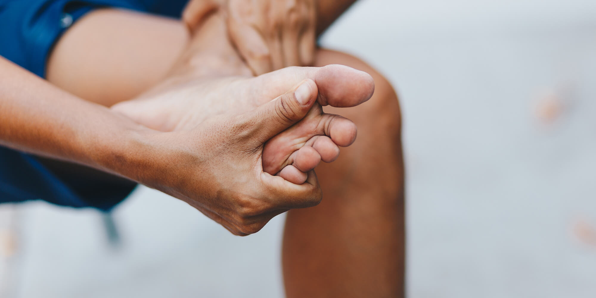 Clinique podiatrique Stéphanie Brodeur | Gros plan sur les jambes d'un homme se massant les pieds